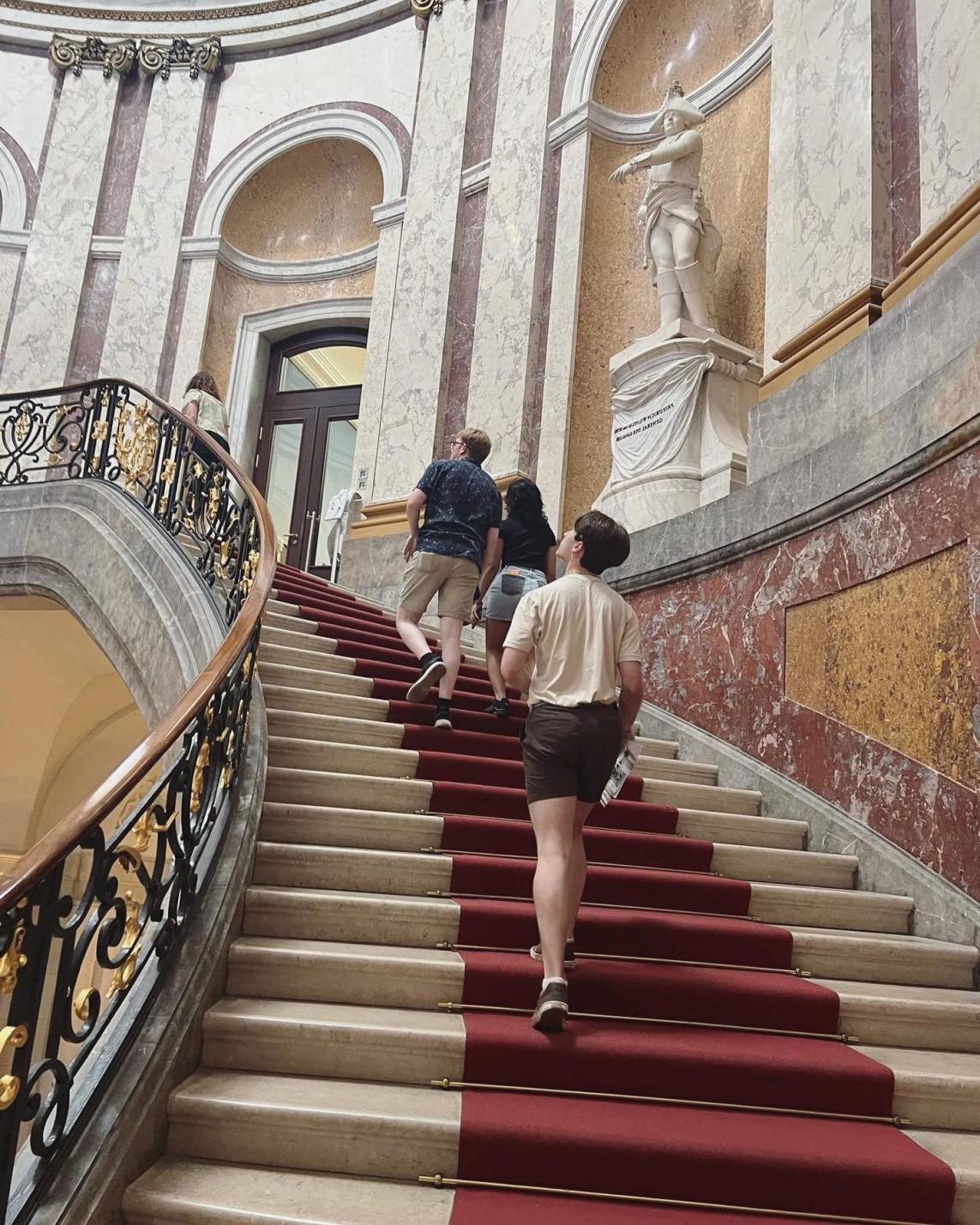 Three people going up old style staircase.